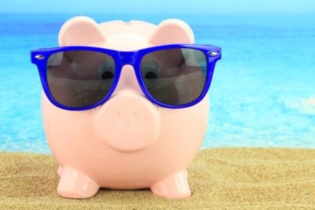 piggy bank on the beach wearing sunglasses