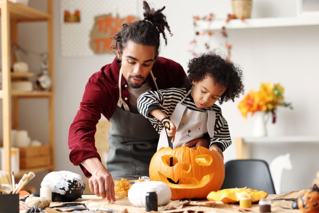 young boy and father carving a pumpkin for Halloween