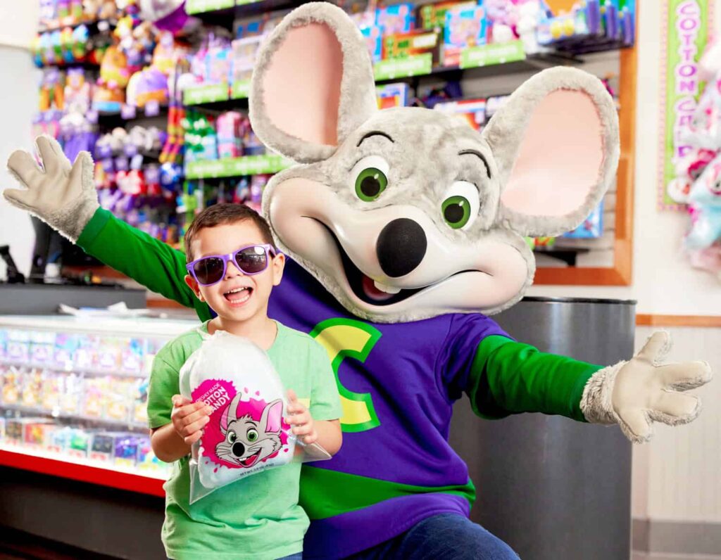 Young boy with mouse character at Chuck E. Cheese