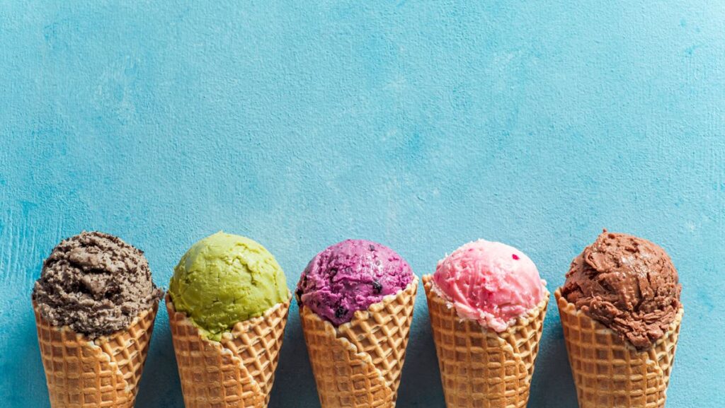 A row of ice cream flavors in waffle cones 